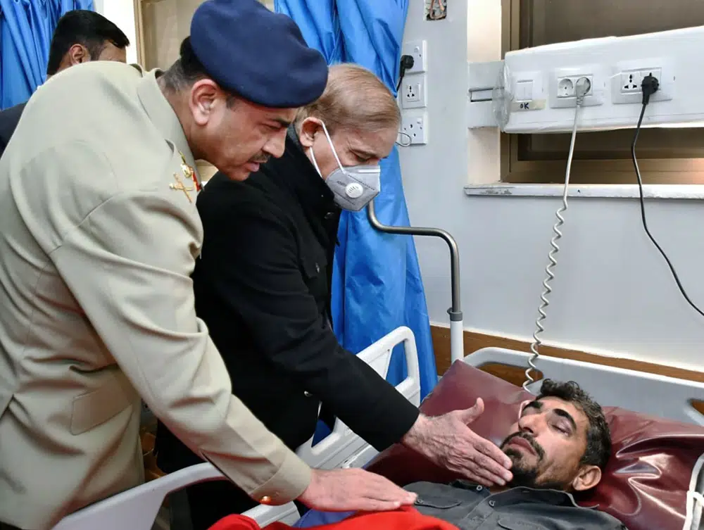 Fotografía proporcionada por el Departamento de Información de Prensa del primer ministro de Pakistán Shehbaz Sharif, segundo de la izquierda, y el jefe del ejército, general Asim Munir, consolando a una víctima de un ataque suicida al interior de una mezquita durante su visita al hospital en Peshawar, Pakistán, el lunes 30 de enero de 2023. (Press Information Department vis AP)