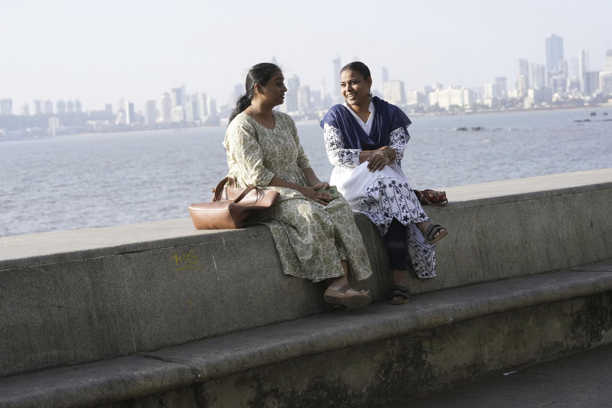 Sunita Sutar, right, speaks with a friend Nirmiti Bhor at Nariman Point in Mumbai, India, Sunday, March 19, 2023. In her village of Shirsawadi in India's Maharashtra state, girls were often married off when they turned 18, but Sutar ached for a different future. She focused on school, where she topped exam after exam. Today, she lives in Mumbai, India's frenetic financial capital, where she works as an auditor for the Indian Defence Department a government job coveted by many young Indians for its security, prestige and benefits. (AP Photo/Rajanish Kakade)