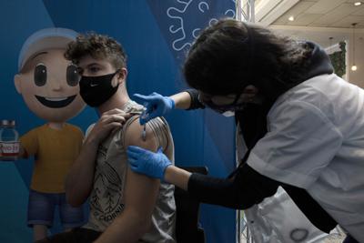 Un joven israelí recibe una dosis de refuerzo de la vacuna contra el coronavirus de una enfermera de los Servicios de Salud Clalit en el complejo Cinema City, en Jerusalén, el 30 de agosto de 2021. (AP Foto/Maya Alleruzzo)