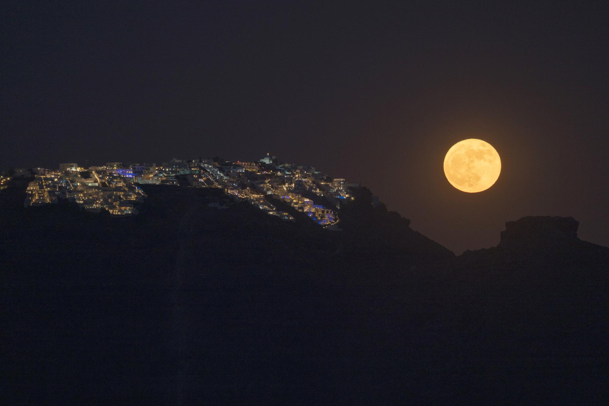 A superlua de morango nasce atrás da vila de Imerovigli, na caldeira de Sandorini, nas ilhas Cíclades, na Grécia, na terça-feira, 14 de junho de 2022. (AP Photo/Petros Giannakouris)