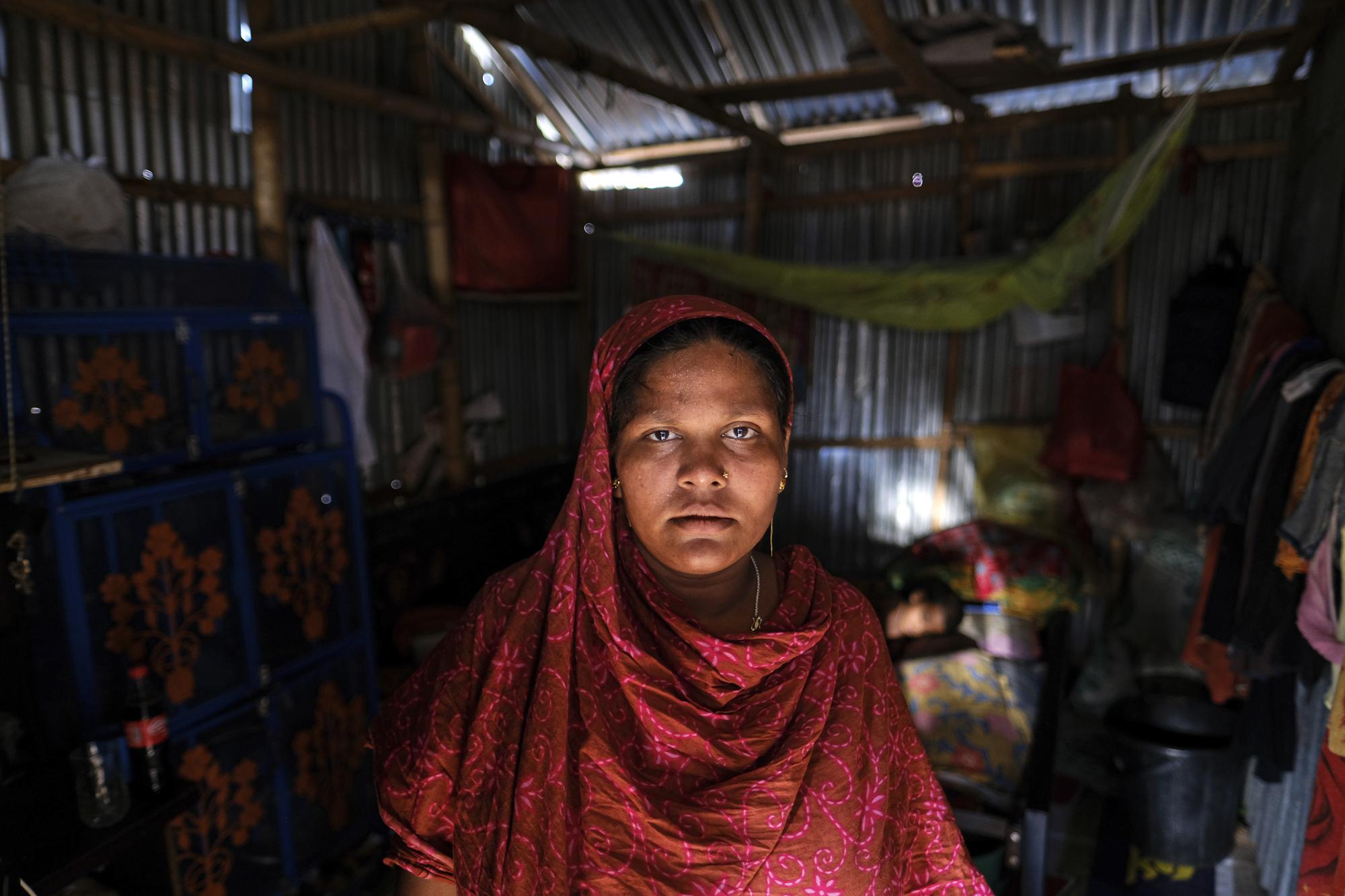 Arzu Begum stands by the door of her house in the poor Mirpur area of Dhaka, Bangladesh on July 3, 2022. Mohammad Jewel and Begum were forced to flee Ramdaspur village in Bangladesh last year when the Meghna River flooded and destroyed their home. The couple and their four sons moved to the capital, Dhaka, where they struggle to pay their rent and food bills on their small incomes. (AP Photo/Mahmud Hossain Opu)
