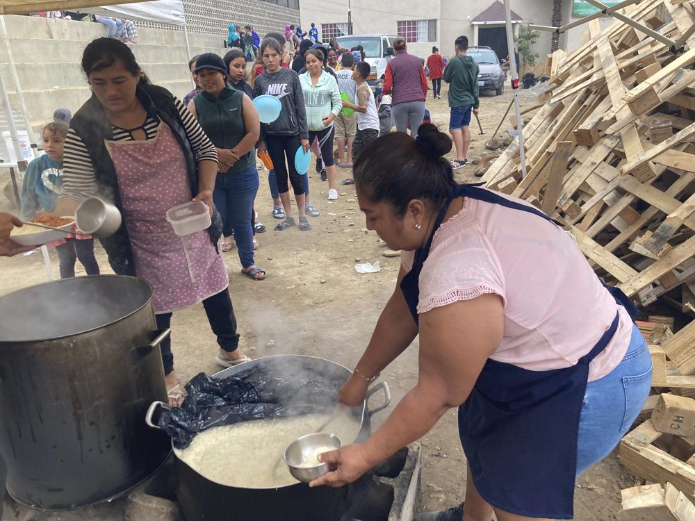 Una mujer sirve una cena a base de arroz y frijoles a migrantes en el Templo Embajadores de Jesús, el mayor albergue para migrantes de la ciudad fronteriza de Tijuana, el 13 de octubre de 2022. El nuevo plan de EEUU que amplía las restricciones de asilo a los venezolanos supone un reto añadido para la ya desbordada red de albergues en México, que apenas puede hacer frente a la creciente llegada de extranjeros. Washington aceptará hasta 24.000 migrantes venezolanos que cumplan una serie de requisitos y devolverá a México a quienes entren de forma ilegal. (AP Foto/Elliot Spagat)