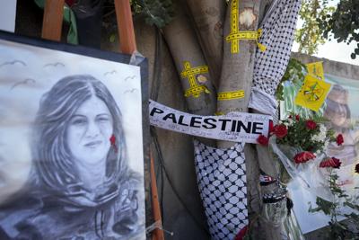 La cinta amarilla marca los agujeros de bala en un árbol y un retrato y flores crean un monumento improvisado en el sitio donde la periodista palestina-estadounidense de Al-Jazeera Shireen Abu Akleh fue asesinada a tiros en la ciudad cisjordana de Jenin, el jueves 19 de mayo de 2022. Casi dos semanas después de la muerte de Abu Akleh, una reconstrucción de The Associated Press respalda las afirmaciones tanto de las autoridades palestinas como de los colegas de Abu Akleh de que la bala que la atravesó provino de un arma israelí. (AP Photo/Majdi Mohammed)