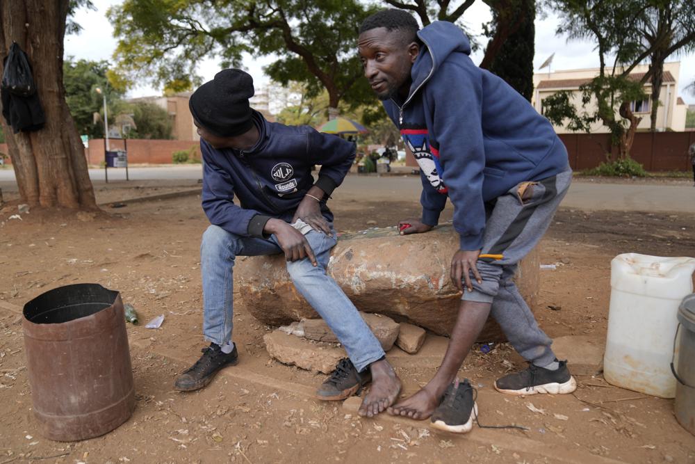Street vendors take off their shoes to show their toes on the streets of Harare, Zimbabwe, Thursday, June, 9, 2022. Rampant inflation is making it increasingly difficult for people in Zimbabwe to make ends meet. Since the start of Russia’s war in Ukraine, official statistics show that Zimbabwe’s inflation rate has shot up from 66% to more than 130%. The country's finance minister says the impact of the Ukraine war is heaping problems on the already fragile economy. (AP Photo/Tsvangirayi Mukwazhi)