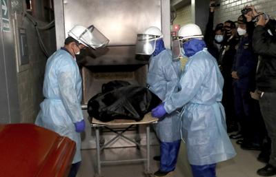 En esta foto proporcionada por el Ministerio del Interior de Perú, los trabajadores del crematorio colocan el cuerpo de Abimael Guzmán, fundador y líder del movimiento guerrillero Sendero Luminoso, en un horno en Callao, Perú, el viernes 24 de septiembre de 2021. (Rolly Reyna / Ministerio del Interior de Perú vía AP)