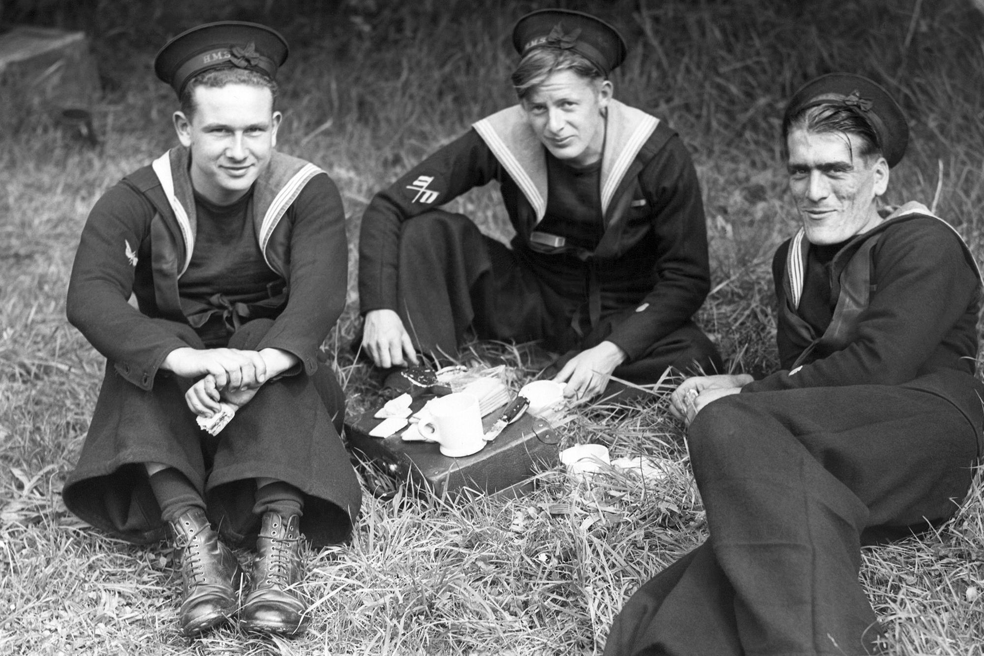 DOSYA - Normandiya sahilinde çalışan İngiliz Mayın Tarlası askerleri 15 Haziran 1944'te ilk kıyı izinlerinin tadını çıkarıyorlar. Soldan sağa: Putney'den Telegraphis EF Guyatt, Woodford Essex'ten Signalman EY Hammonds ve Romford Essex'ten Wireman VJ Howe piknik yaşları ile çimenler.  (AP Fotoğrafı, Dosya)