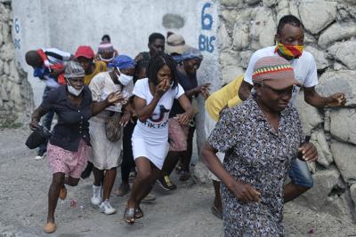 Personas que marchaban hacia la residencia del primer ministro para exigir justicia por el asesinato del presidente haitiano Jovenel Moïse corren de los gases lacrimógenos que arrojó la policía, el miércoles 20 de octubre de 2021, en Puerto Príncipe Haití. (AP Foto/Matias Delacroix)