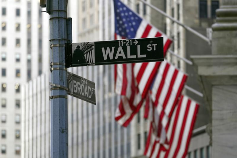 FILE - The Wall St. street sign is framed by the American flags flying outside the New York Stock exchange, on Jan. 14, 2022, in the Financial District. Stocks are opening lower on Wall Street on Tuesday, May 31, 2022, and crude oil prices rose sharply after European leaders agreed to cut nearly all imports of oil from Russia over the next six months. (AP Photo/Mary Altaffer, File)