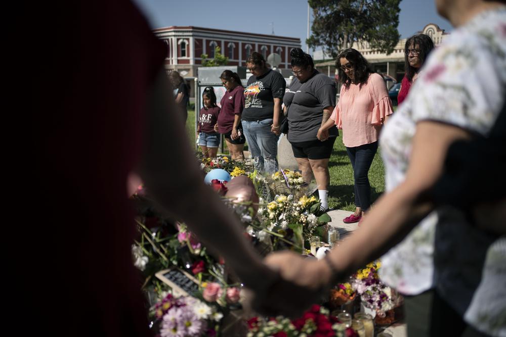 McKenzie Hinojosa, 28, fourth from left, prays for her cousin Eliahana Torres and other victims, at a memorial site for victims killed in the Robb Elementary school shooting, Saturday, May 28, 2022, in Uvalde, Texas. (AP Photo/Wong Maye-E)