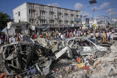 Gente caminando entre la destrucción dejada por dos coches bomba en una transitada intersección en Mogadiscio, Somalia, el domingo 30 de octubre de 2022. (AP Foto/Farah Abdi Warsameh)