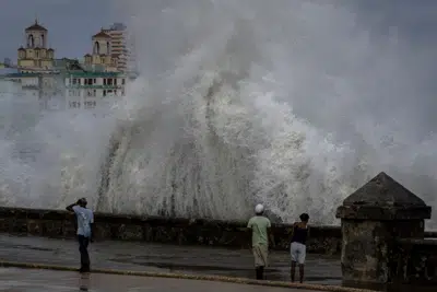 ARCHIVO - Unas personas en un muelle mientras olas enormes chocan contra el muro previo a la llegada del huracán Ian en La Habana, Cuba, el miércoles 28 de septiembre de 2022. (AP Foto/Ramon Espinosa, Archivo)