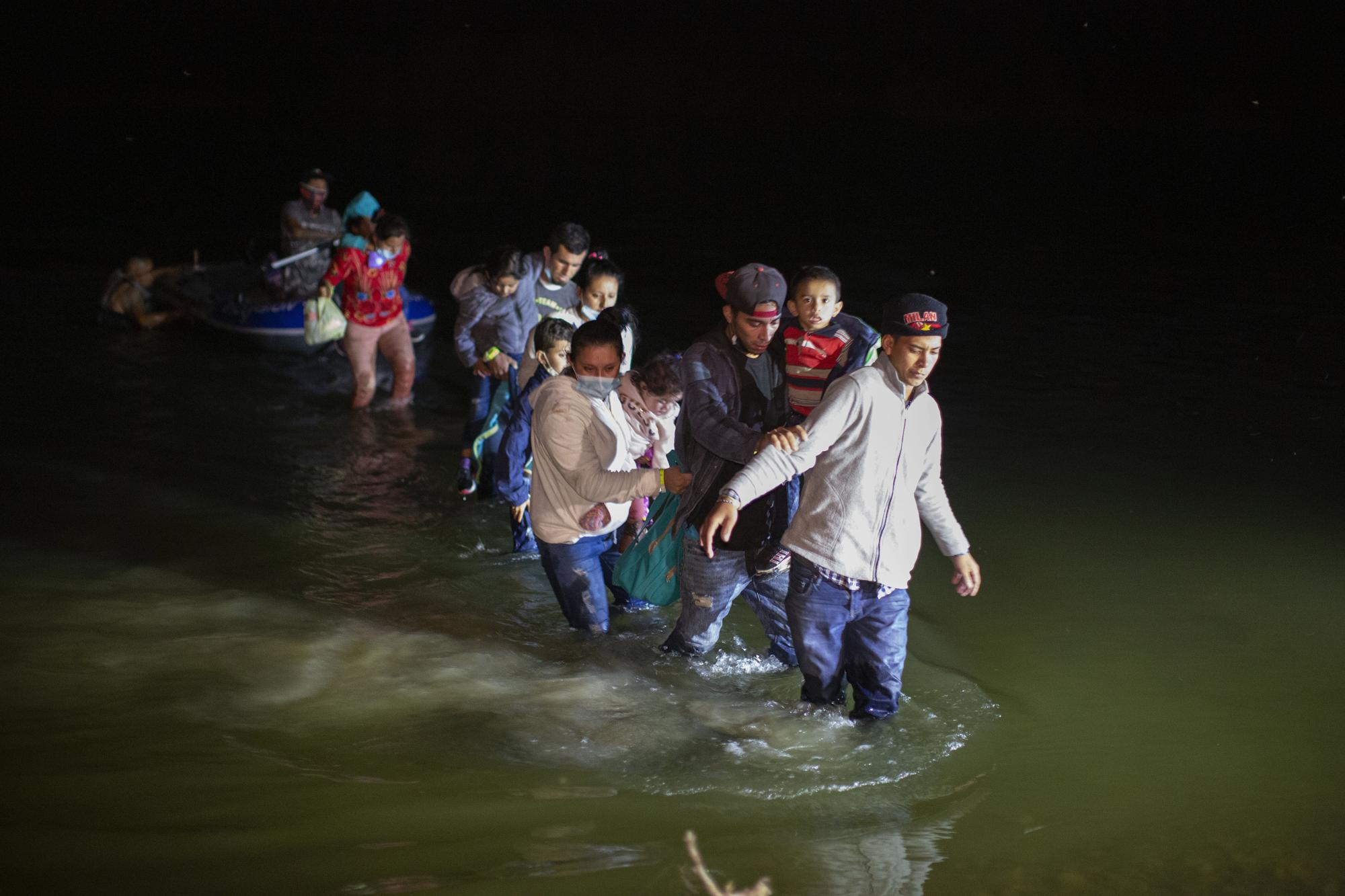 FILE - Migrant families wade through shallow waters towards Roma, Texas, March 24, 2021. Biden took office on Jan. 20 and almost immediately, numbers of migrants exceeded expectations. (AP Photo/Dario Lopez-Mills, File)