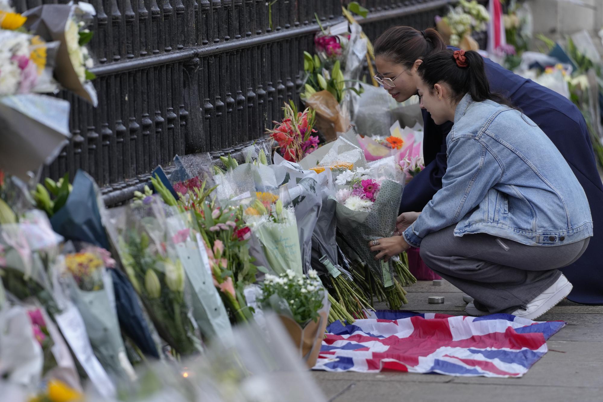 Mourners lay flowers outside Buckingham Palace in London, Friday, Sept. 9, 2022. Queen Elizabeth II, Britain's longest-reigning monarch and a rock of stability across much of a turbulent century, died Thursday Sept. 8, 2022, after 70 years on the throne. She was 96. (AP Photo/Kirsty Wigglesworth)