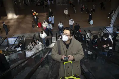 Viajeros en escaleras mecánicas en la Estación de Ferrocarril del Oeste de Beijing, el miércoles 18 de enero de 2023. (AP Foto/Mark Schiefelbein)