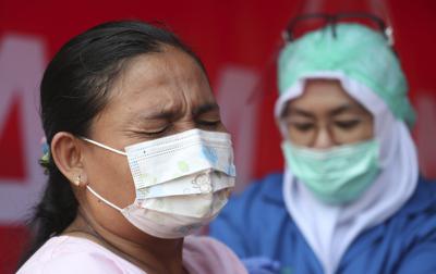 Una mujer recibe la vacuna de AstraZeneca durante una campaña de vacunación masiva para trabajadores del transporte público en la terminal de autobús de Kampung Rambutan en Yakarta, Indonesia, el jueves 10 de junio de 2021. (AP Foto/Achmad Ibrahim)