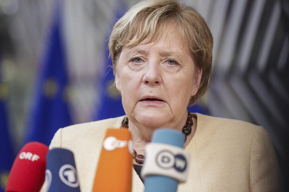 Germany's Chancellor Angela Merkel talks to journalists as she arrives for an EU summit in Brussels, Thursday, Oct. 21, 2021. European Union leaders head into a standoff between Poland and most of the other EU member nations over the rule of law in the eastern member state. Other issues for the 27 EU leaders include climate change, the energy crisis, COVID-19 developments and migration. (Olivier Hoslet, Pool Photo via AP)