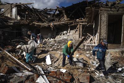 Local residents collect wood for heating from a destroyed school where Russian forces were based, in the recently retaken area of Izium, Ukraine, Monday, Sept. 19, 2022. Residents of Izium, a city recaptured in a recent Ukrainian counteroffensive that swept through the Kharkiv region, are emerging from the confusion and trauma of six months of Russian occupation, the brutality of which gained worldwide attention last week after the discovery of one of the world's largest mass grave sites.  (AP Photo/Evgeniy Maloletka)