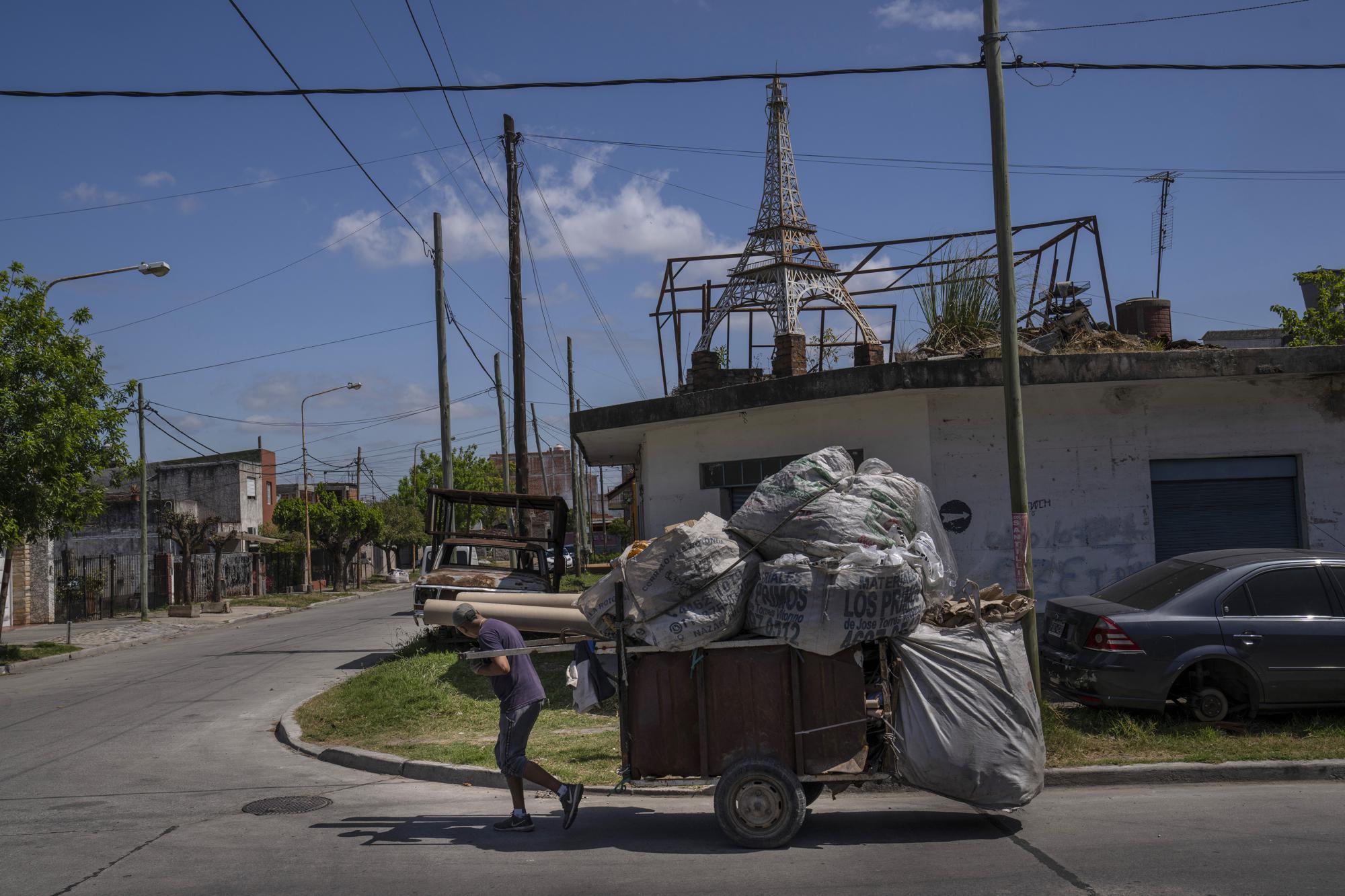 Un reciclador de cartÃ³n tira de su carrito frente a la casa de Miguel MuÃ±oz, donde una rÃ©plica de la Torre Eiffel se encuentra en un techo, elevada sobre una pila de ladrillos, en La Tablada, Argentina, el martes 18 de octubre de 2022. (AP Foto/Rodrigo Abd)