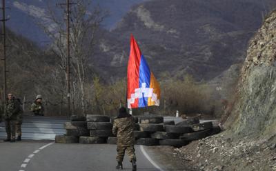 Un soldado de la etnia armenia camina con la bandera de Nagorno Karabaj el miércoles 25 de noviembre de 2020 en dirección a un retén cerca del poblado de Charektar. Éste se encuentra en la región separatista de Nagorno Karabaj, en una nueva frontera con el distrito Kalbajar entregado a Azerbaiyán. (AP Foto/Sergei Grits)