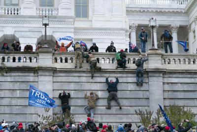 ARCHIVO - En esta fotografía de archivo del 6 de enero de 2021, partidarios del entonces presidente Donald Trump trepan el muro oeste del Capitolio de Estados Unidos en Washington. (AP Foto/Jose Luis Magaña, Archivo)