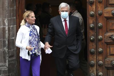 El presidente mexicano Andrés Manuel López Obrador, a la derecha y con máscaras protectoras para evitar el contagio del nuevo coronavirus, y la primera dama Beatriz Gutiérrez se alejan después de votar en la Ciudad de México, el domingo 6 de junio de 2021. Los mexicanos eligen a toda la cámara baja del Congreso, casi la mitad de los gobernadores del país y la mayoría de los alcaldes, en una votación que determinará si el partido Morena del presidente López Obrador obtiene la mayoría legislativa necesaria para continuar con su “Cuarta transformación” de México. (Foto AP/Marco Ugarte)