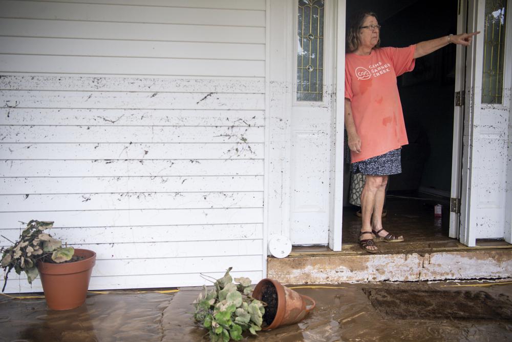 With a waterline of dirt and small debris still clinging to her home, Joy Rhodes points to the flooded Garner Creek on Saturday, Aug. 21, 2021, in Dickson, Tenn. (Josie Norris/The Tennessean via AP)