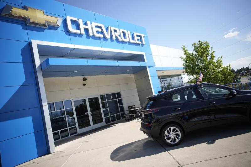 FILE - In this Sunday, Sept. 12, 2021, file photo, a pair of unsold 2022 Bolt electric vehicles sit outside a Chevrolet dealership in Englewood, Colo.  U.S. new vehicle sales tumbled in September as a global shortage of computer chips worsened, shuttering factories and limiting the selection on dealer lots. (AP Photo/David Zalubowski, File)