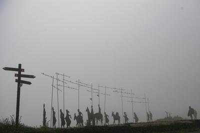 Peregrinos caminan junto a esculturas que indican la dirección del Camino de Santiago en la montaña El Perdón, cerca de Pamplona, España, el martes 1 de junio de 2021. (AP Foto/Alvaro Barrientos)