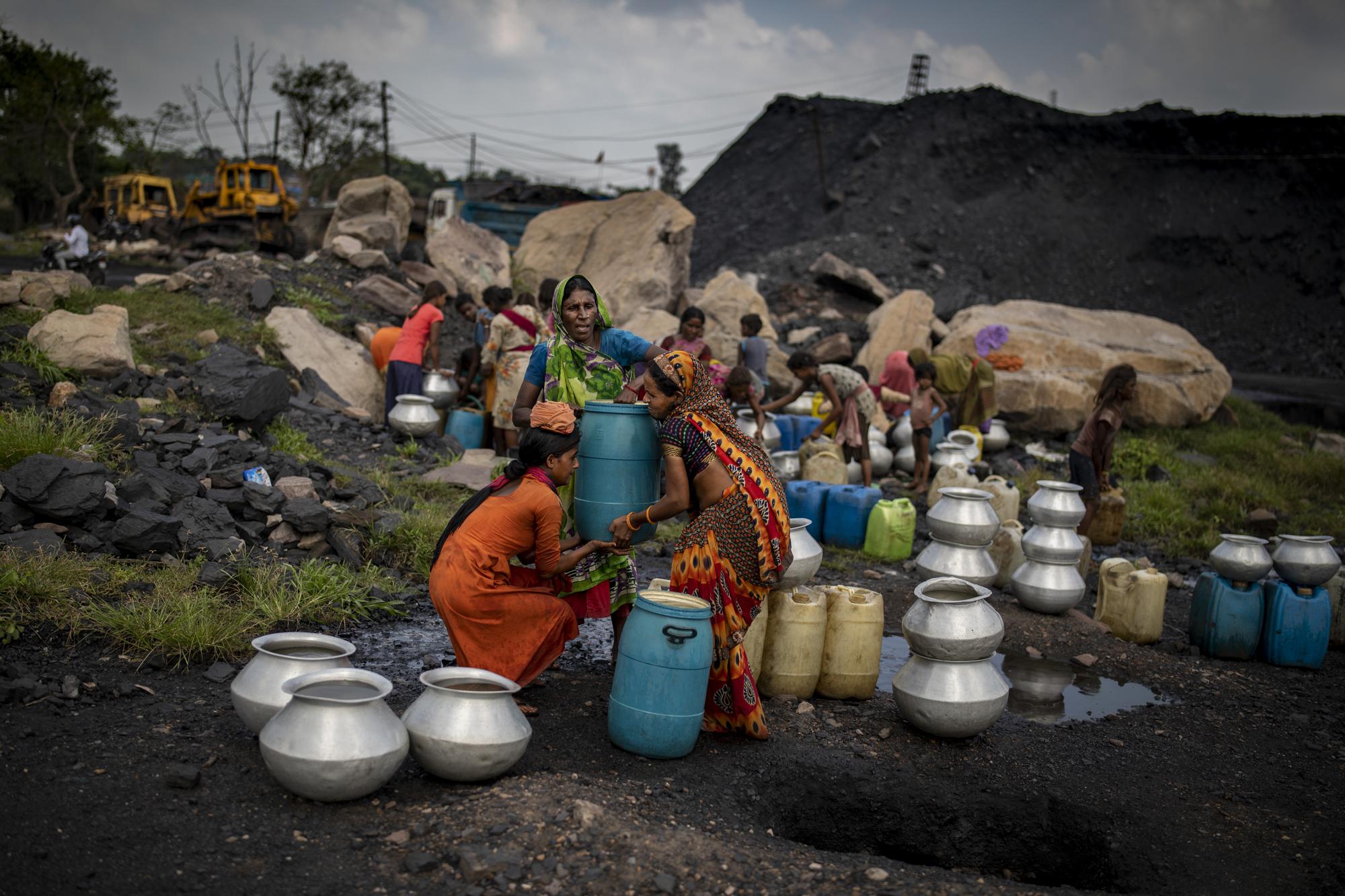 Members of coal workers' community fetch drinking water from a pipe at a coal depot near an open-caste mine in Dhanbad, an eastern Indian city in Jharkhand state, Friday, Sept. 24, 2021. A 2021 Indian government study found that Jharkhand state -- among the poorest in India and the state with the nation’s largest coal reserves -- is also the most vulnerable Indian state to climate change. Efforts to fight climate change are being held back in part because coal, the biggest single source of climate-changing gases, provides cheap electricity and supports millions of jobs. It's one of the dilemmas facing world leaders gathered in Glasgow, Scotland this week in an attempt to stave off the worst effects of climate change. (AP Photo/Altaf Qadri)