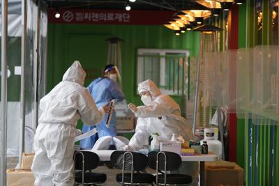 Trabajadores de salud con equipo de protección se preparan para tomar muestras en una clínica temporal de detección del coronavirus el miércoles 29 de diciembre de 2021 en Seúl, Corea del Sur. (AP Foto/Lee Jin-man)