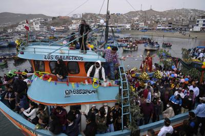 Devotos de San Pedro, el patrón católico de los pescadores, llevan su estatua en un bote durante una procesión por tierra y mar para conmemorar su fiesta en el puerto de Pucusana, Perú, el miércoles 29 de junio de 2022. (Foto AP/Martín Mejía)