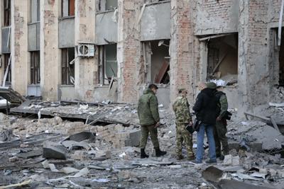 Investigadores revisan el sitio de un ataque cerca de un edificio administrativo en Donetsk, la capital de la autoproclamada República Popular de Donetsk, el domingo 16 de octubre de 2022, en el este de Ucrania. (AP Foto/Alexei Alexandrov)