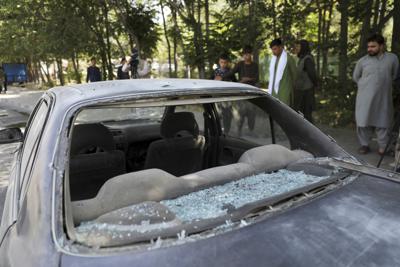 Hombres afganos miran a un auto dañado tras la explosión de una bomba caminera en Kabul, Afganistán, el domingo 6 de junio de 2021. (AP Foto/Rahmat Gul)