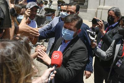 El presidente electo de Chile, Gabriel Boric, centro, saluda a sus seguidores al llegar al palacio presidencial de La Moneda para reunirse con el presidente Sebastián Piñera en Santiago, Chile, el lunes 20 de diciembre de 2021 (AP Foto/Matías Delacroix)