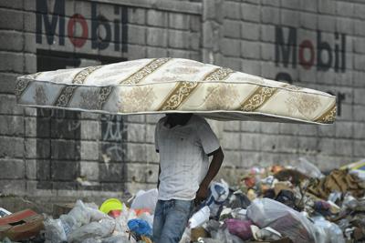 Un hombre camina con un colchón sobre su cabeza en Puerto Príncipe, Haití, el miércoles 27 de octubre de 2021. (AP Foto/Matias Delacroix)