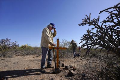 El artista Álvaro Enciso coloca una cruz en un sitio donde fueron hallados restos de presuntos migrantes fallecidos tratando de cruzar el desierto cerca de Three Points, Arizona, el 18 de mayo del 2021. (AP Photo/Ross D. Franklin)