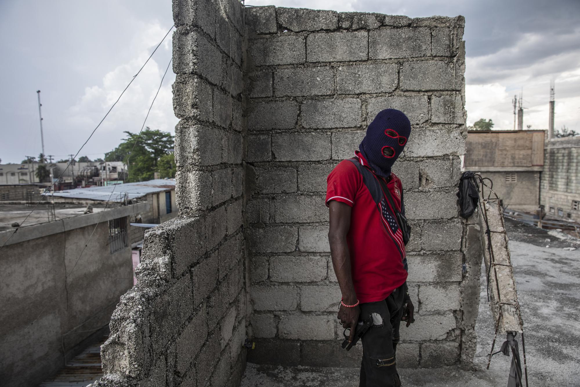 A gang member, wearing a balaclava and holding a gun, poses for a photo in the Portail Leogane neighborhood of Port-au-Prince, Haiti, Thursday, Sept. 16, 2021. There could be as many as 100 gangs in Port-au-Prince; no one has an exact count and allegiances often are violently fluid. (AP Photo/Rodrigo Abd)