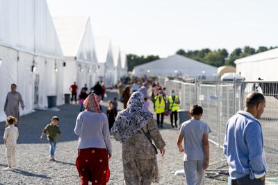 ARCHIVO - Refugiados afganos caminan a través de un campamento de refugiados afganos en la Base Conjunta McGuire Dix Lakehurst, Nueva Jersey, el 27 de septiembre de 2021. El último de los miles de refugiados afganos que esperaban ser reasentados en ocho instalaciones militares estadounidenses partió de la base de Nueva Jersey el sábado 19 de febrero de 2022. Están completando un viaje que comenzó con la caótica evacuación de Kabul en agosto. (AP Photo/Andrew Harnik, Archivo)