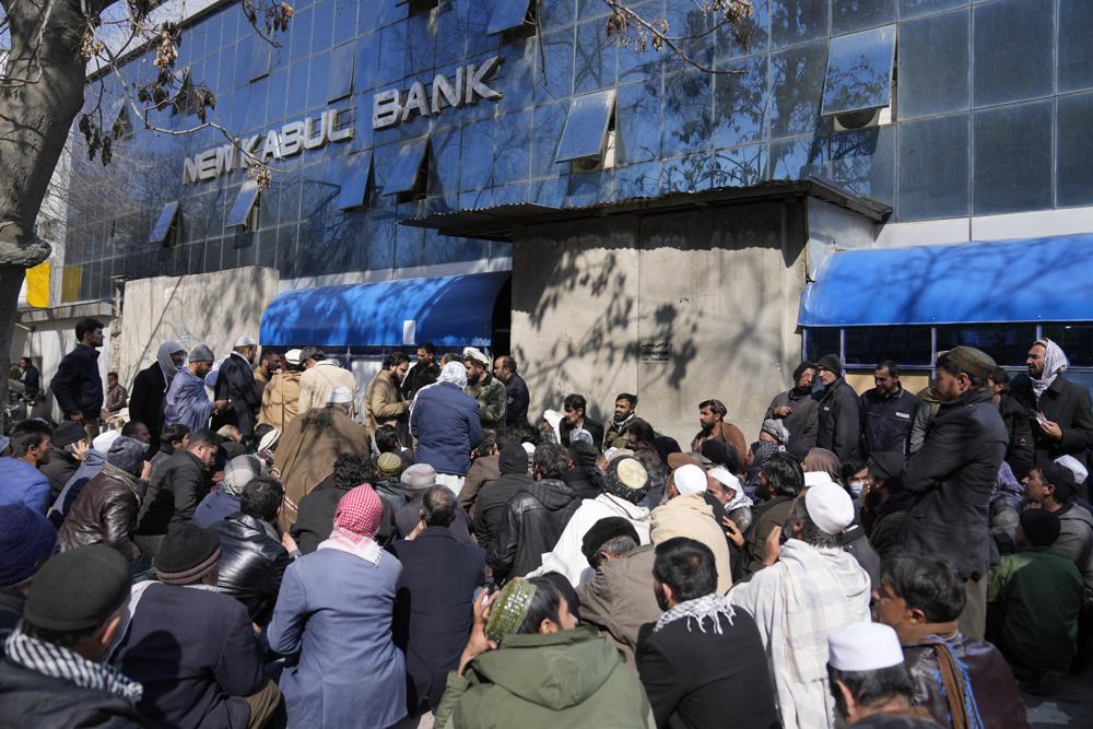 Afghan wait to enter a bank, in Kabul, Afghanistan, Sunday, Feb. 13, 2022. Six months since Kabul was ceded to the Taliban with the sudden and secret departure of U.S.-backed president residents say a calm has settled on the country, but the future is uncertain as the economy teeters on the verge of an economic collapse and the new Taliban rulers tackle the transition from war to relative peace. (AP Photo/Hussein Malla)