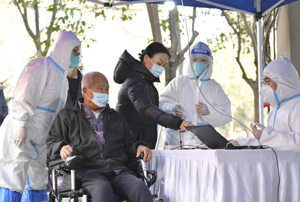 In this photo released by China's Xinhua News Agency, people register for tests at a COVID-19 testing site in Xi'an in northwestern China's Shaanxi Province, Tuesday, Dec. 21, 2021. China on Wednesday ordered millions of people locked down in neighborhoods and workplaces in the northern city of Xi'an following a spike in coronavirus cases. (Shao Rui/Xinhua via AP)