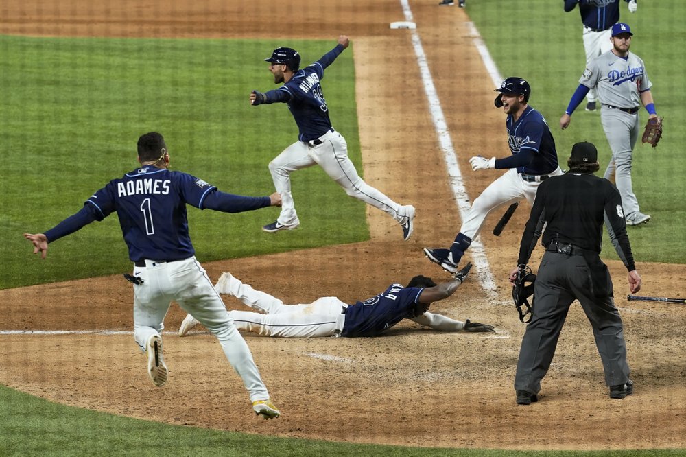 Randy Arozarena está tendido en el terreno tocando el home plate mientras los Rays de Tampa Bay celebran la victoria dejando en el terreno a los Dodgers de Los Ángeles para finalizar el Juego 4 de la Serie Mundial 2020 de la MLB el Sábado 24 de octubre de 2020.