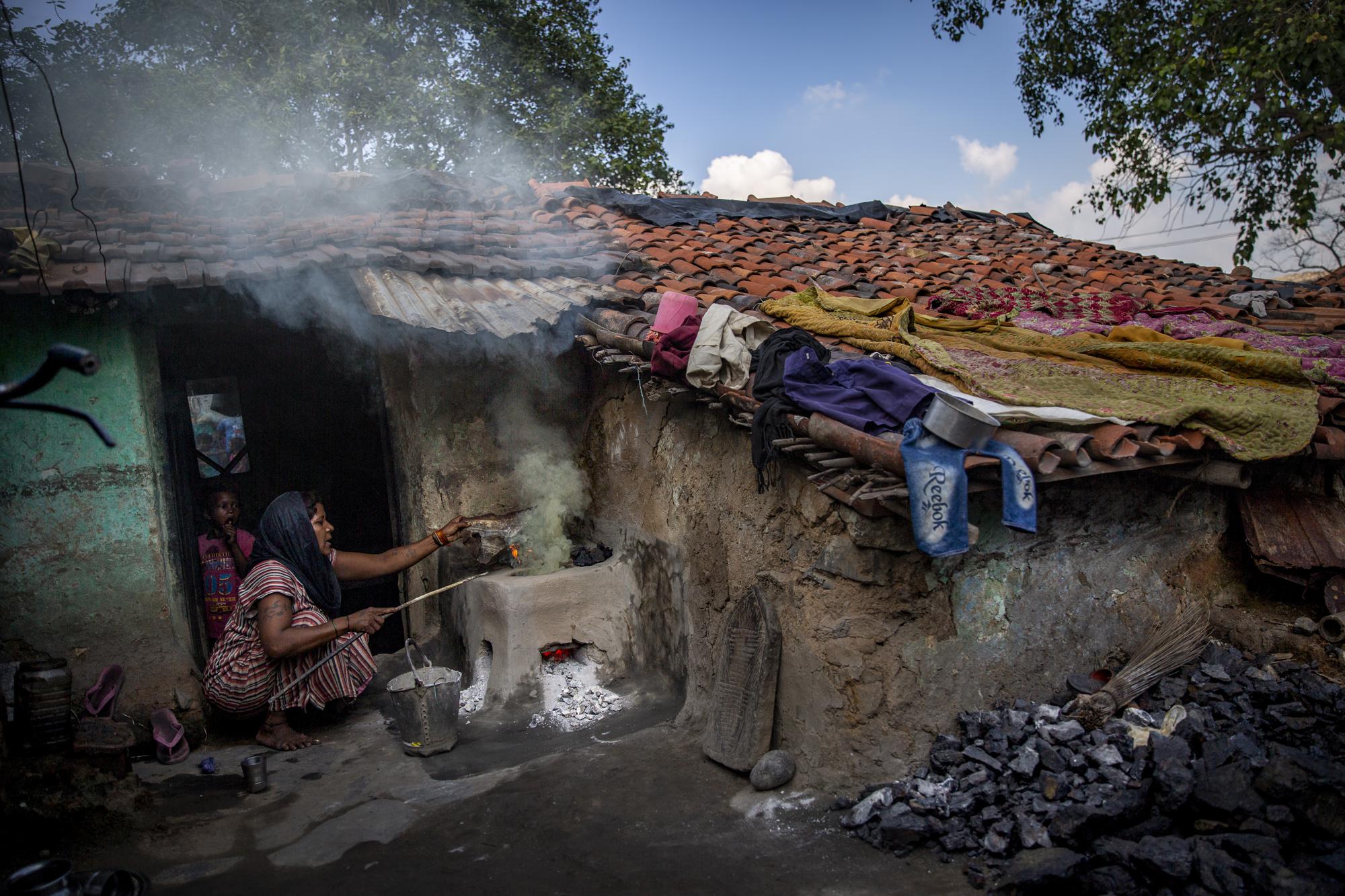 Murti Devi, who scavenges coal for living, prepares a hearth fueled by coal at a village near Dhanbad, an eastern Indian city in Jharkhand state, Friday, Sept. 24, 2021. The 32-year-old single mother of four lost the job she had all her life when the mine she worked for closed four years ago. Nothing came of the resettlement plans promised by the coal company so she, like so many others, turned to scavenging coal. On good days, she’ll make a dollar. On other days, she relies on neighbors for help. “If there is coal, then we live. If there isn’t any coal, then we don’t live,” she said. (AP Photo/Altaf Qadri)