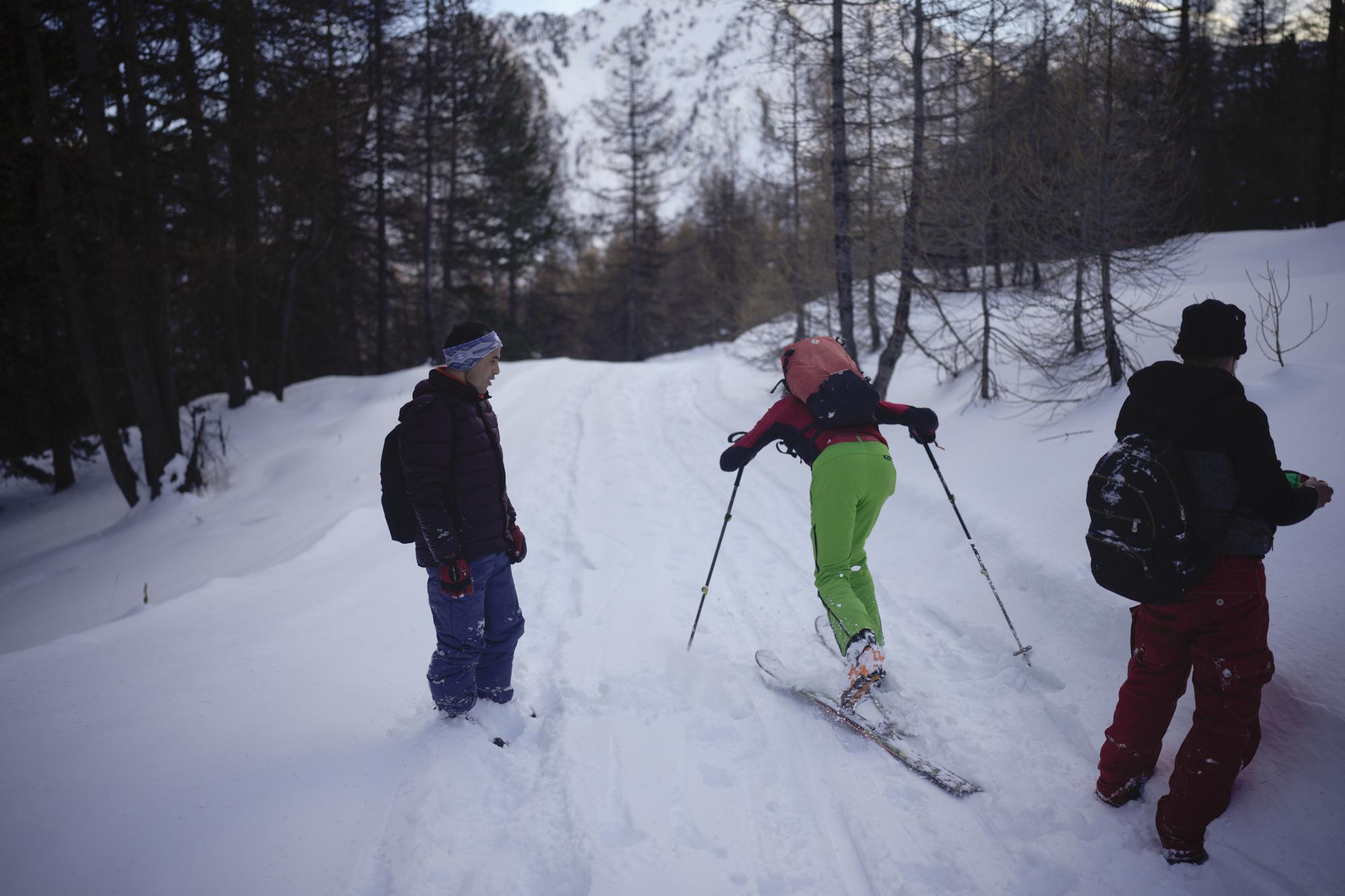 Afghan migrant Sayed Hamza watches a skier pass by as he and Ali Rezaie trek through the French-Italian Alps to reach a migrant refuge in Briancon, France, Sunday, Dec. 12, 2021. When the Taliban seized power in Afghanistan in August, some Afghans resolved to escape and embarked on forbidding journeys of thousands of kilometers to Europe. Ali Rezaie's odyssey through five countries has carried him high into the French-Italian Alps, where he is pushing through knee-deep snow to evade border guards. (AP Photo/Daniel Cole)