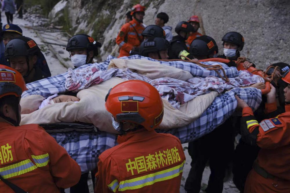 In this photo released by Xinhua News Agency, rescuers transfer survivors following an earthquake in Moxi Town of Luding County, southwest China's Sichuan Province on Monday, Sept. 5, 2022. Dozens people were reported killed and missing in a 6.8 magnitude earthquake that shook China's southwestern province of Sichuan on Monday, triggering landslides and shaking buildings in the provincial capital of Chengdu, whose 21 million residents are already under a COVID-19 lockdown. (Cheng Xueli/Xinhua via AP)