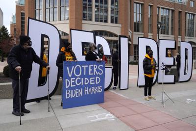 ARCHIVO - Unas personas sostienen letreros afuera de un centro de convenciones de Wisconsin, previo a un recuento de votos de las elecciones presidenciales, el 20 de noviembre de 2020. (AP Foto/Nam Y. Huh, Archivo)