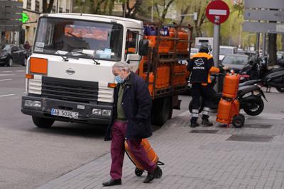 A man wheels a butane gas bottle he just bought from a delivery truck in Madrid, Spain, Monday, March 28, 2022. Spain's government is readying a package of emergency economic measures worth 6 billion euros (6.6 billion dollars) in direct aid and tax breaks and 10 billion euros (11 billion dollars) in loans for families and businesses affected by the consequences of Russia's invasion of Ukraine. Since Russia invaded Ukraine last month oil prices have also spiked and driven up gas prices. (AP Photo/Paul White)