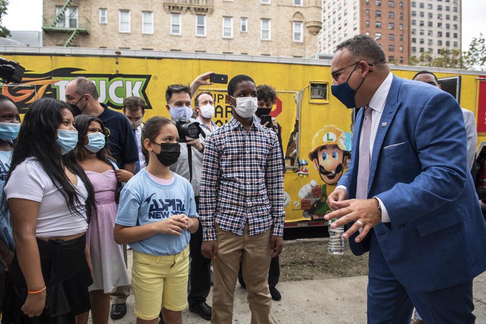 FILE - In this Tuesday, Aug. 17, 2021 file photo, Education Secretary Miguel Cardona speaks to students outside P.S. 5 Port Morris, a Bronx elementary school in New York. With new federal pandemic funding, he says,“This is our moment to ensure that we reopen, reinvest and reimagine our schools differently and better than ever before,” Cardona said at a virtual education summit in June. “These next months and years will determine the trajectory of success for millions of students in our care.” (AP Photo/Brittainy Newman)