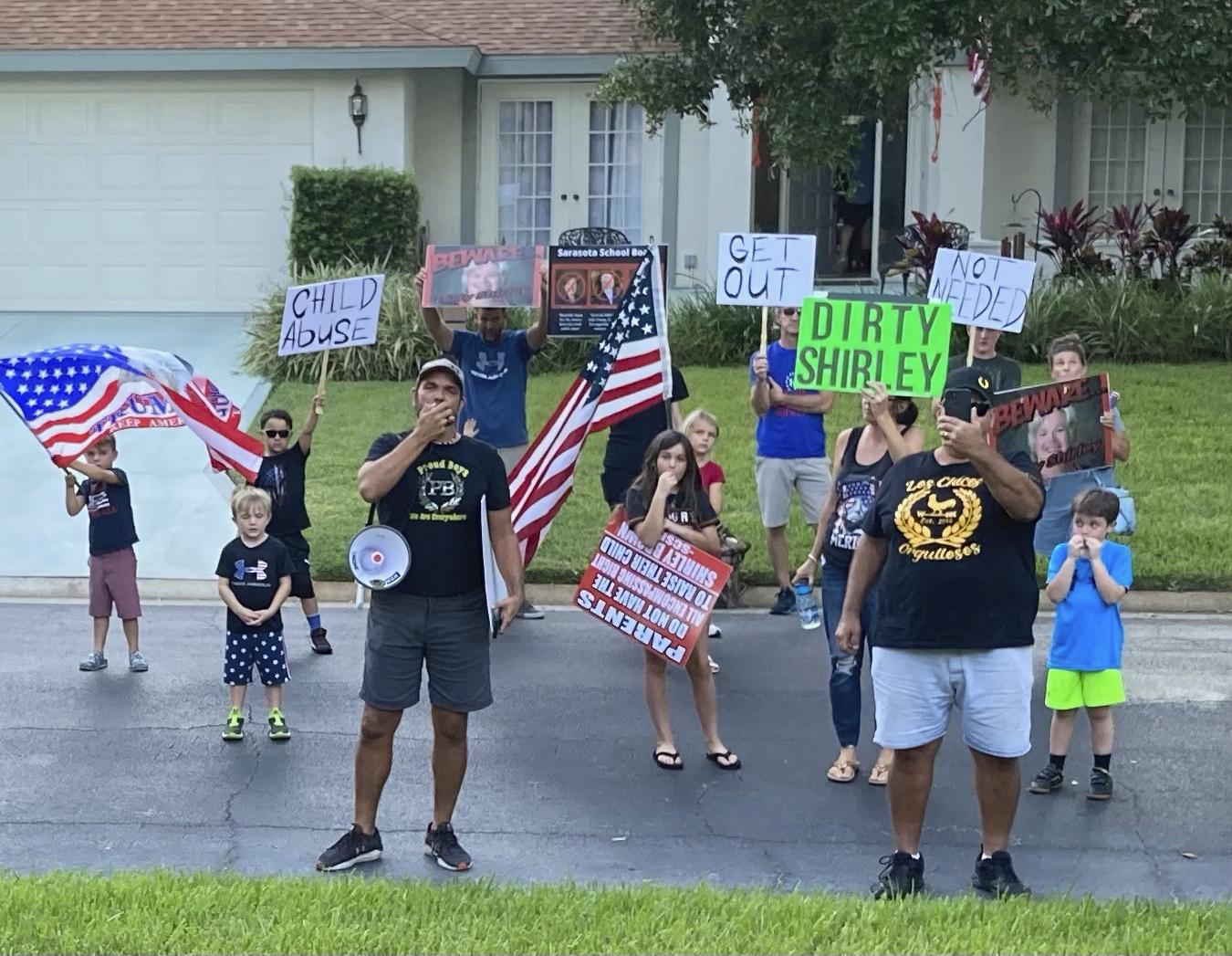 In this photo provided by former Sarasota County School Board Chair Shirley Brown, Proud Boy member James Hoel and others gather outside her home for an anti-mask protest on Oct. 4, 2021. We see you in there, Shirley. We want you to come out for a redress of grievances, Hoel said through a megaphone. (Shirley Brown via AP)