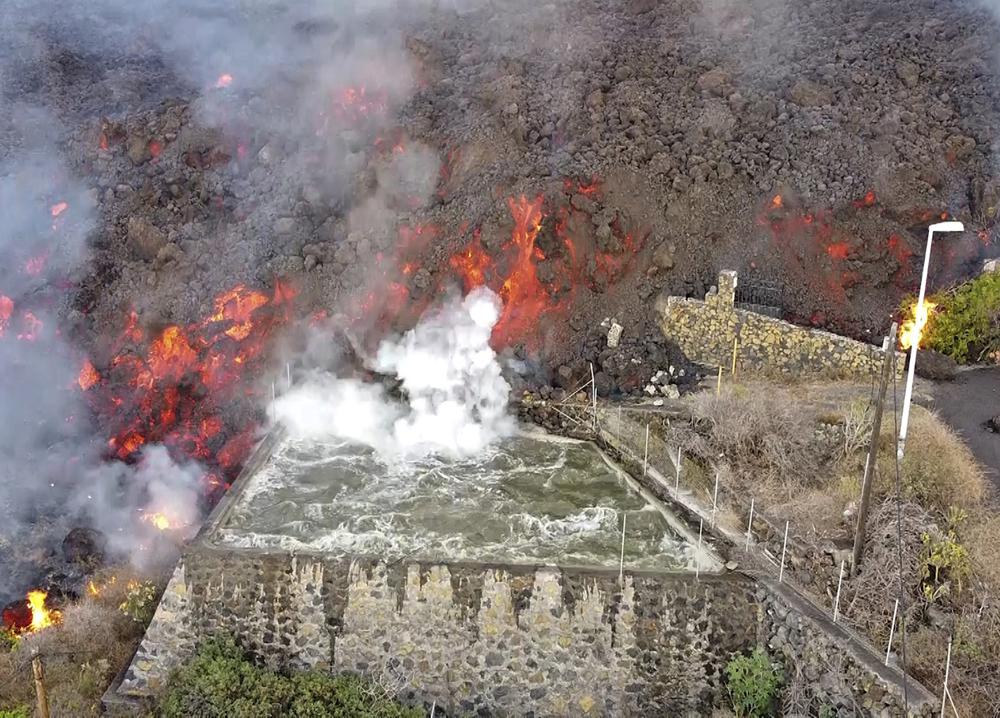 La lava caliente llega a una balsa que normalmente se utiliza para el riego después de la erupción de un volcán en la isla de La Palma en las Canarias, España, el lunes 20 de septiembre de 2021. Ríos de lava gigantes caen lenta pero implacablemente hacia el mar después de un volcán. estalló en una isla española frente al noroeste de África.  La lava está destruyendo todo a su paso, pero las evacuaciones rápidas ayudaron a evitar víctimas después de la erupción del domingo.  (Europa Press vía AP)