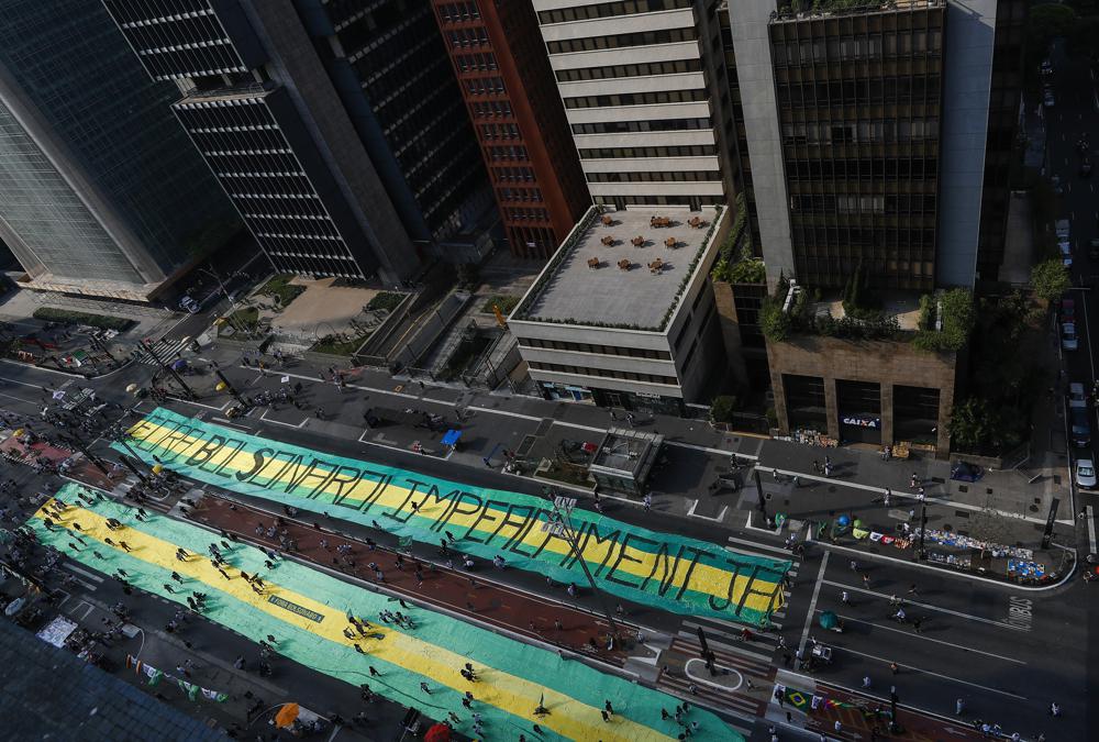 Opposition groups extend a giant banner that reads in Portuguese Bolsonaro Get Out, Impeachment now, during a protest against Brazilian President Jair Bolsonaro, at Avenida Paulista, Sao Paulo, Brazil, Sunday, Sep. 12, 2021. Opposition groups marched against President Jair Bolsonaro, demanding his resignation for mishandling the pandemic, corruption over vaccine contracts and a poor economy. (AP Photo/Marcelo Chello)